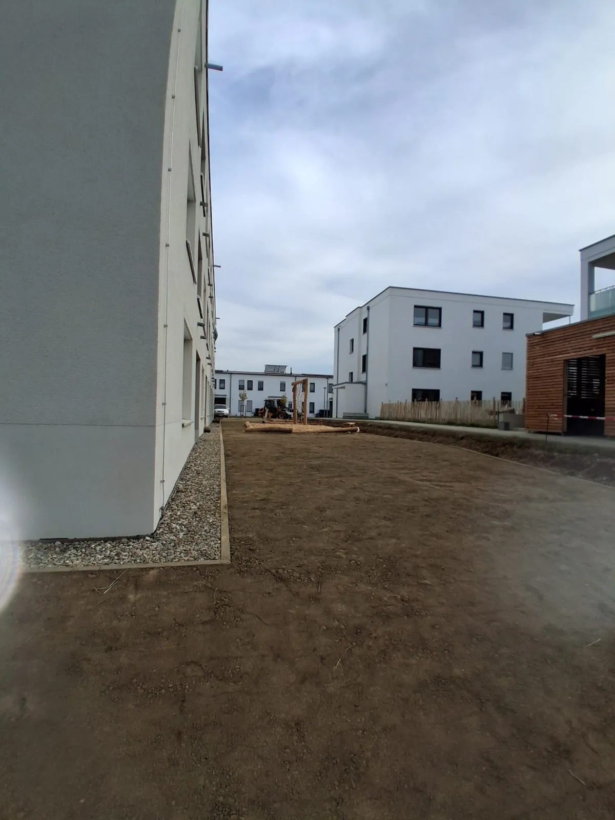 Planierter Boden und Kiesstreifen an einem neuen Wohnhaus, vorbereitet für Rasen