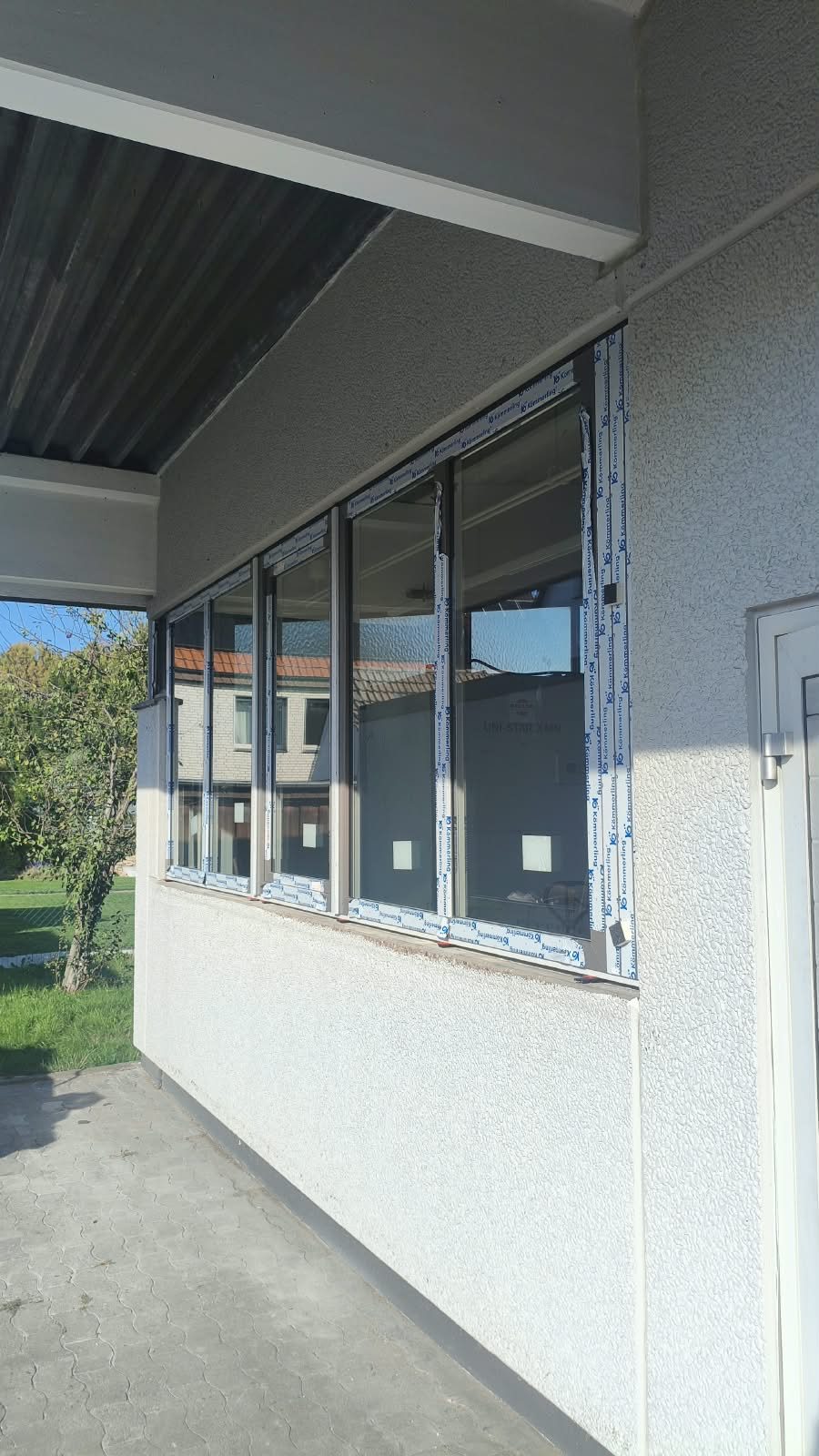 Eingebaute Kömmerling-Kunststofffenster mit Schutzfolie vor der Montage der Fensterbänke