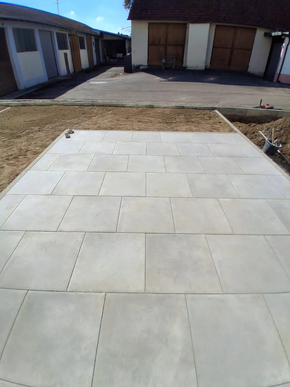 Neu verlegte großformatige Betonplatten mit Bordsteinen im Hof eines Wohnhauses