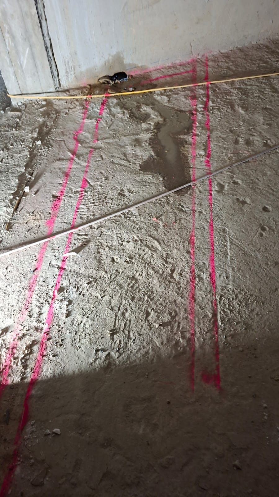Mit pinkem Markierspray angezeichnete Schlitzlinien auf dem Betonboden